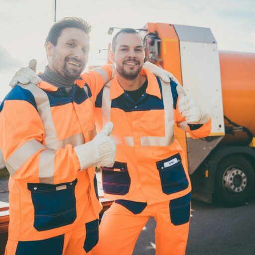 Zwei Bauarbeiter in Warnkleidung vor Lastwagen