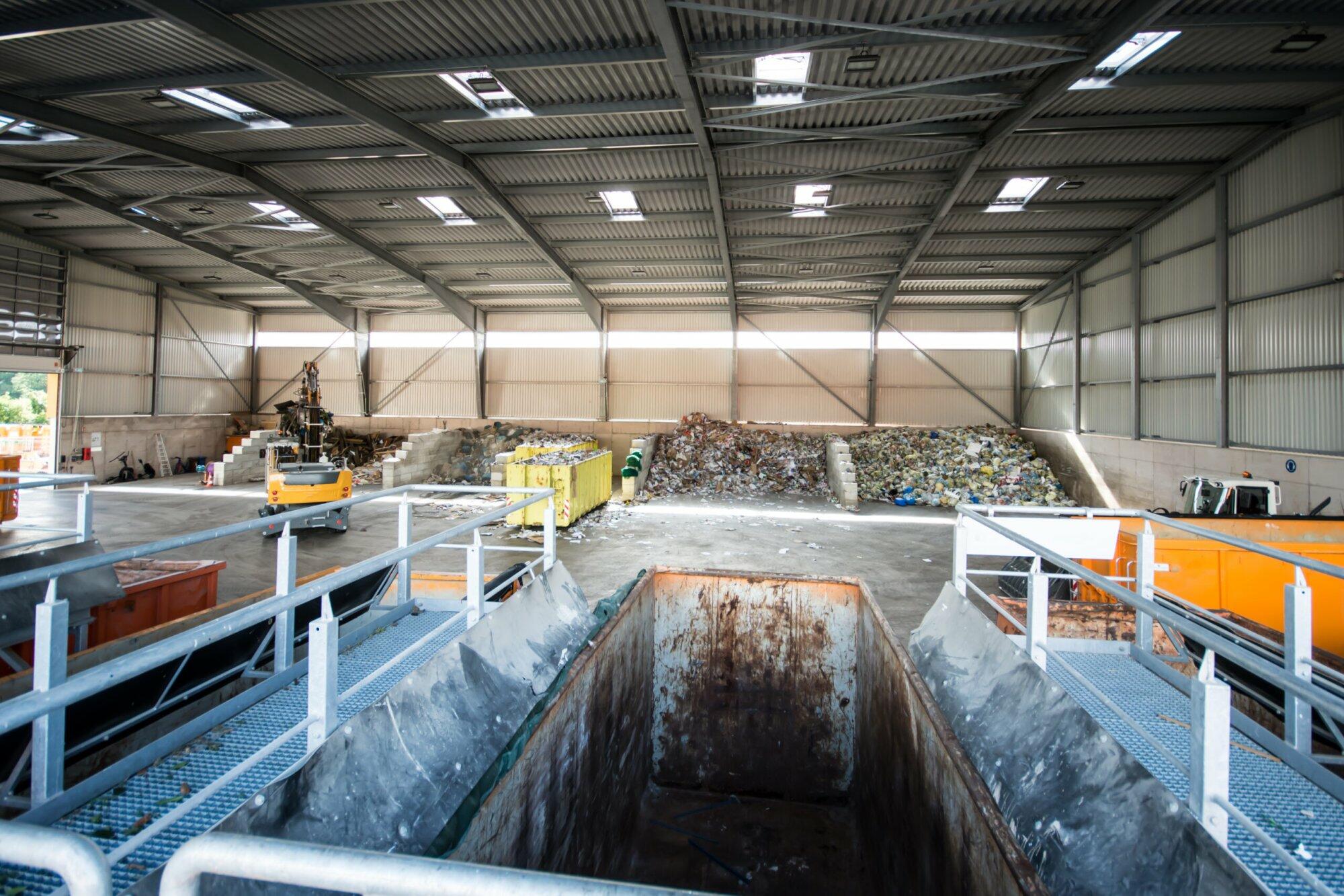 Recyclinghalle mit Müllbergen und Containern